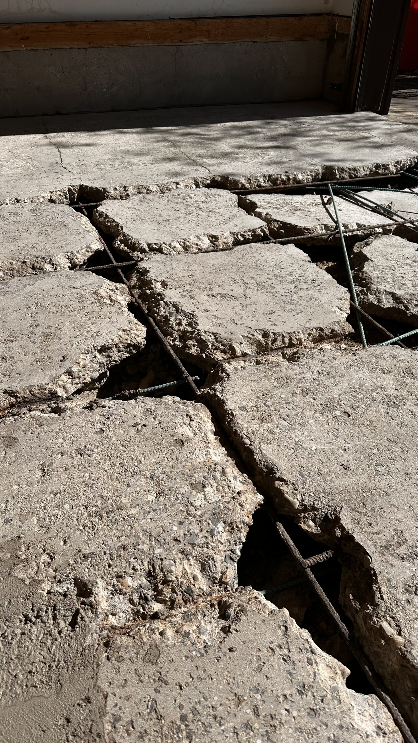 Concrete Repair Services Jacksonville, FL | Con Cure USA IMG 8159 Cracked concrete floor with exposed rebar, showing disrepair and structural issues in sunlight.