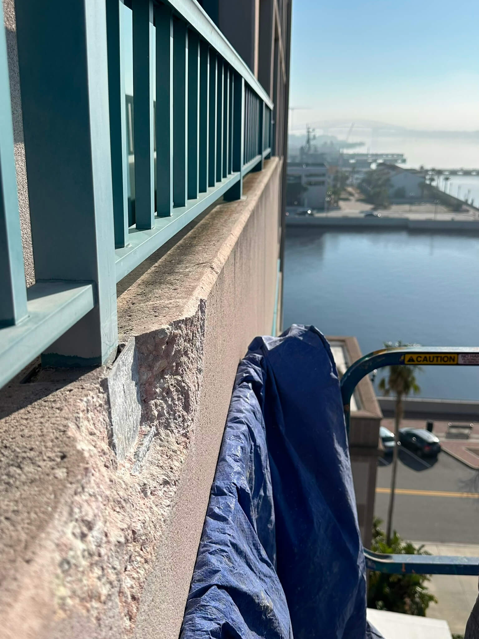 A blue tarp is draped over the railing of a building, providing protection from the elements.